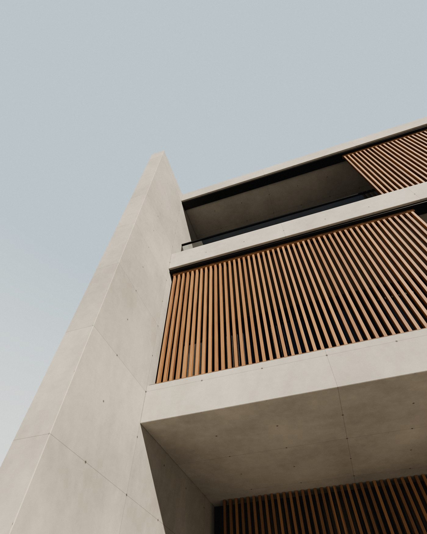 Blick an einer Fassade aus Sichtbeton empor: auskragende Geschossdecken, Schiebeläden aus Eichenholz-Lamellen und eine schmale Wandscheibe vor hellem Himmel